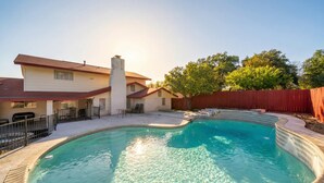 A backyard with a swimming pool, a covered patio, and a red wooden fence. - Spacious 4BR with Private Pool, Near Six Flags (San Antonio)