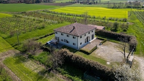 A white building with a tiled roof, surrounded by green fields and hills.