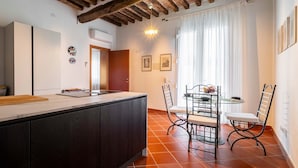 A modern kitchen with a wooden ceiling, a dining area with a table and chairs, and a window with curtains.