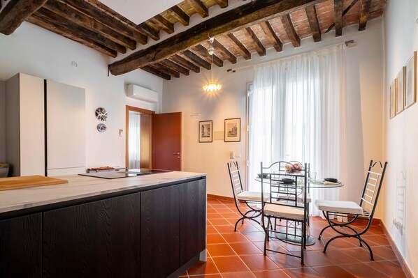 Une cuisine moderne avec un plafond en bois, un coin repas avec une table et des chaises, et une fenêtre avec des rideaux.