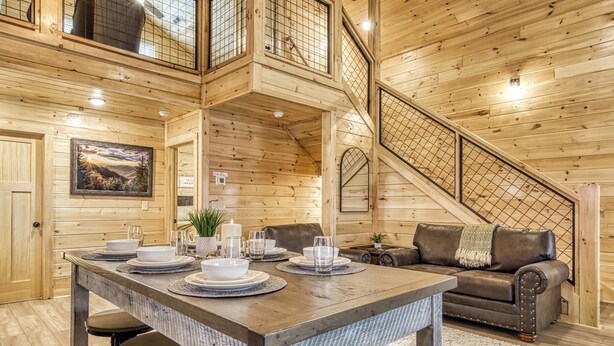 Un intérieur en bois comprenant une table à manger pour quatre personnes, un canapé et un escalier.