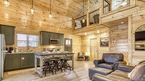 Un intérieur spacieux de chalet en bois, comprenant une cuisine, un coin repas et un espace détente.