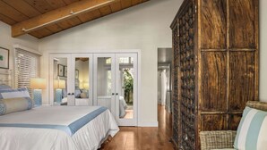 A bedroom with a large bed, a wicker sofa, and a wooden wardrobe. - Classic Cottage in the Heart of La Jolla Shores (San Diego)