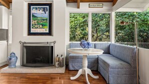 A modern living room with a fireplace, a blue sofa, and a dining table. - Classic Cottage in the Heart of La Jolla Shores (San Diego)
