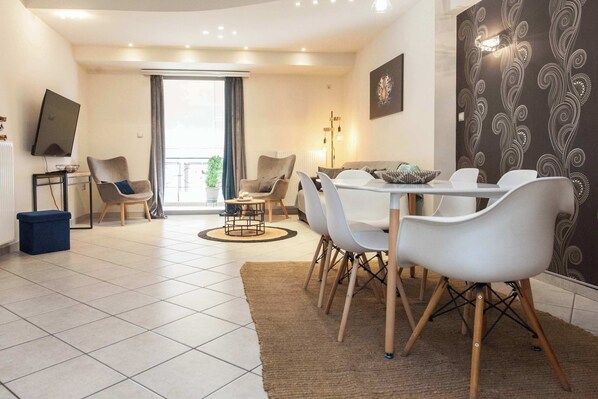 Un salon moderne comprenant un coin repas, un tĂ©lĂ©viseur et une grande fenĂȘtre.
