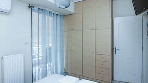 A bedroom with a bed, a wardrobe, a radiator, and a TV. - Elegant Spacious 2Bd Apt with Balcony in Petralona (Athina)