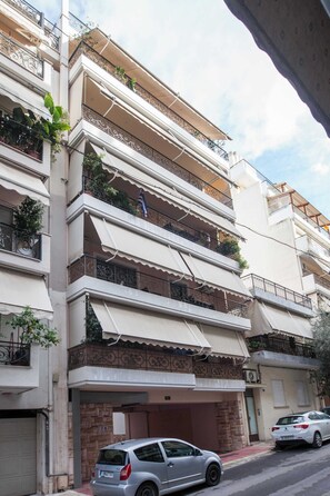 A multi-story residential building with balconies, a garage, and parked cars.
