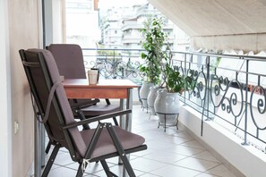 Ein Balkon mit Esstisch und Stühlen, Blumentöpfen und Blick auf Gebäude.