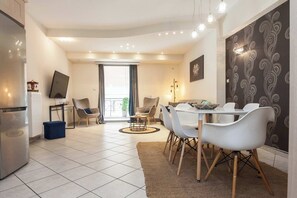Eine moderne Küche mit Backofen, ein Essbereich mit Tisch und Stühlen sowie ein Wohnbereich mit Sofa und Fernseher.