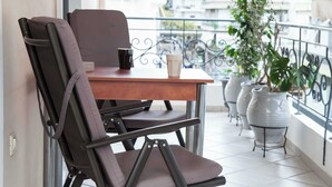 A balcony with a table and chairs, potted plants, and a view of buildings. - Elegant Spacious 2Bd Apt with Balcony in Petralona (Athina)