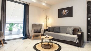 A modern living room with a sofa, armchair, coffee table, and a painting of a tiger. - Elegant Spacious 2Bd Apt with Balcony in Petralona (Athina)