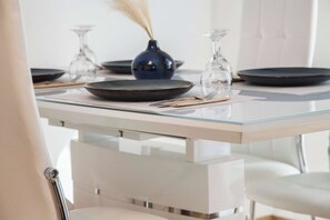 A dining table with a glass top, black plates, and clear glassware. - Stylish Renovated 2 Bd Apt in Exarcheia (Athina)