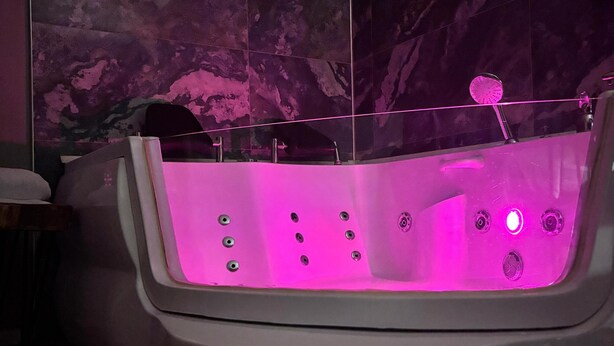 A bathtub with a built-in massage feature, set against a tiled wall. - vera pansıyon (Istanbul)