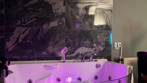A modern bathroom with a freestanding bathtub, marble walls, and a visible towel rack. - vera pansıyon (Istanbul)