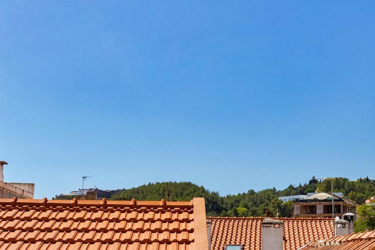 A building with terracotta tiled roofs and a clear blue sky.