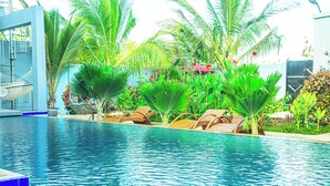 A swimming pool with lounge chairs and palm trees. - Jazira Palace (Pwani Mchangani)