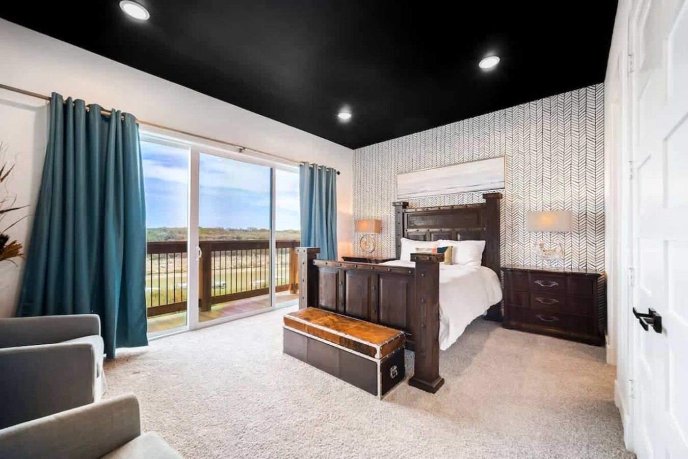 Une chambre avec un grand lit, un banc, une vue sur l’extérieur et un mur décoré de motifs.