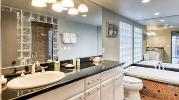 Une salle de bain moderne dotée d’un grand miroir, de deux vasques, de toilettes et d’un espace douche.