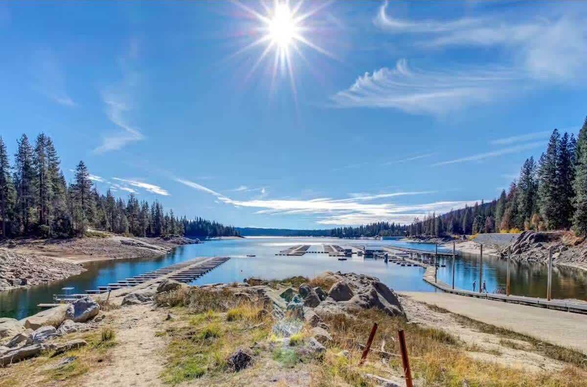 Une rivière traversée par un pont, bordée d’arbres et surplombée d’un ciel dégagé.