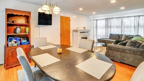 A dining area with a wooden table, chairs, and a bookshelf. - 4 Mi to Dtwn: Pet-friendly Home in Utica (Utica)