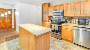 Una cocina moderna con armarios de madera, electrodomésticos de acero inoxidable y una isla con encimera de granito.
