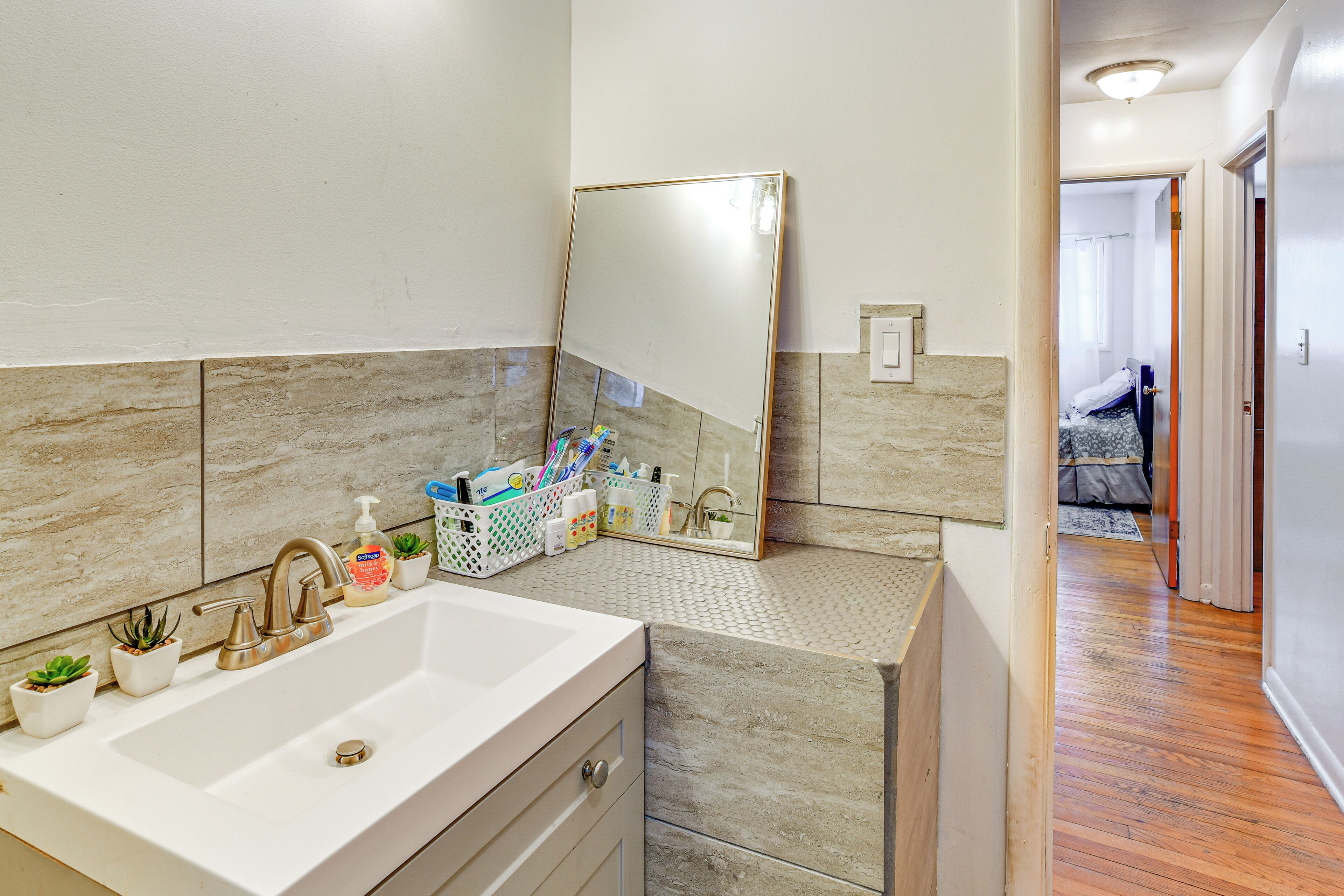 Un baño con un lavabo grande, un espejo y una pequeña planta.