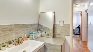Un baño con un lavabo grande, un espejo y una pequeña planta.
