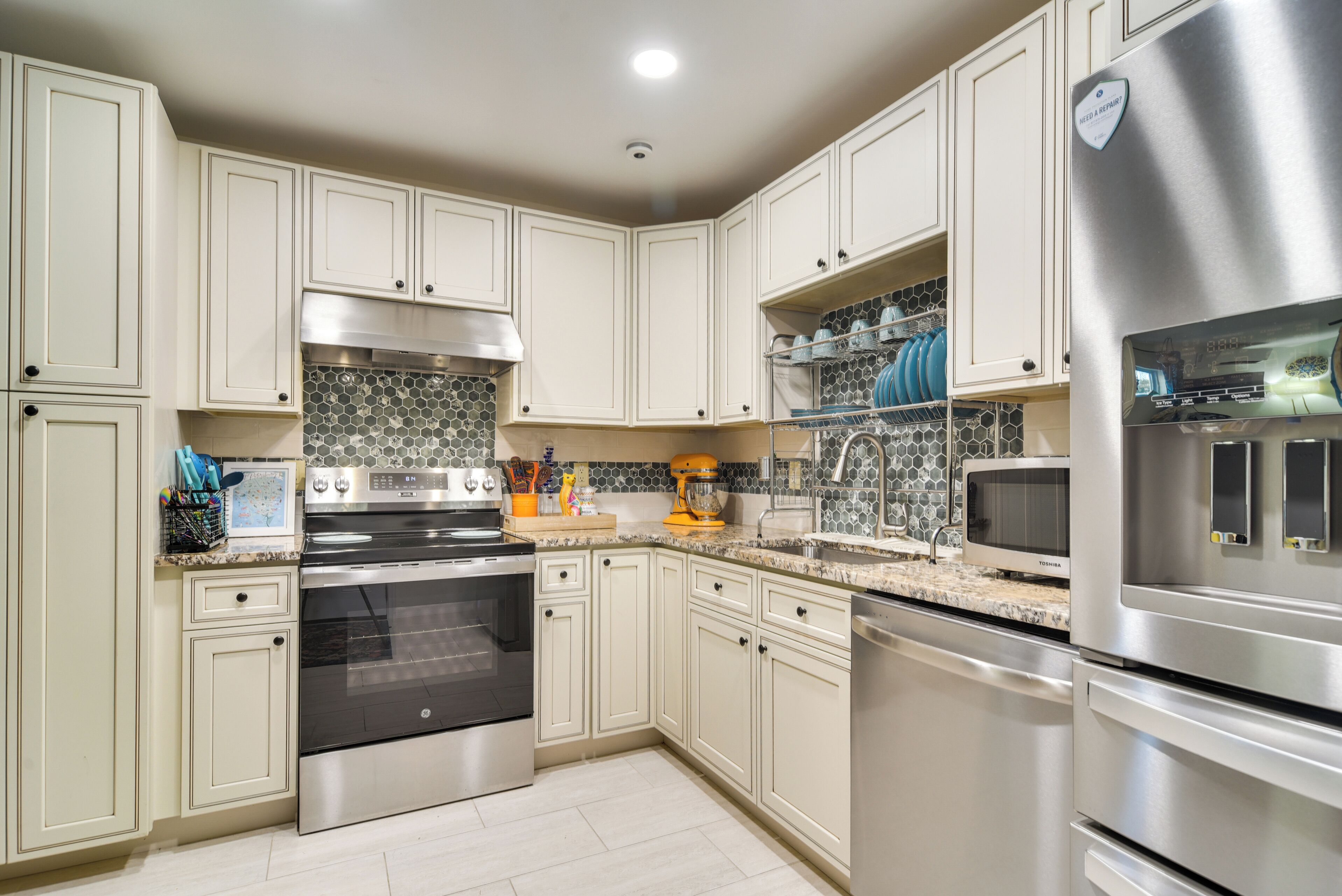A modern kitchen with stainless steel appliances, light-colored cabinets, and a tiled backsplash.