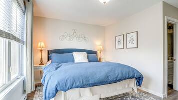 Une chambre à coucher avec un grand lit, deux lampes de chevet, un élément décoratif mural et des tableaux encadrés.