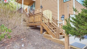 Una casa de madera con porche, escaleras de madera y un pequeño jardín.