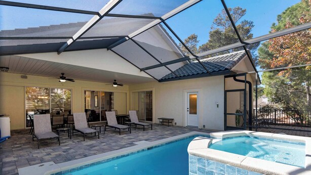 An indoor swimming pool with lounge chairs and a covered patio area. - Gorgeous home with pool and golf cart included! Pet friendly! (Destin)