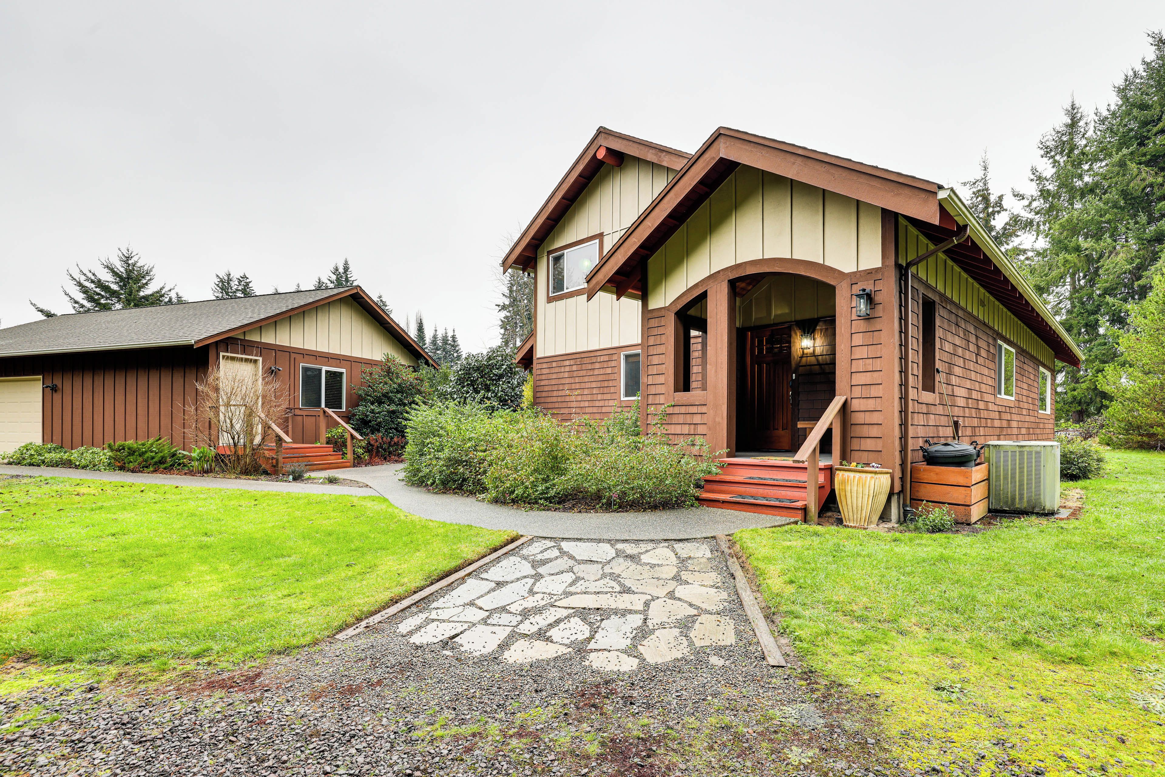 A two-story house with a stone pathway leading to the front door, surrounded by a well-maintained lawn and a small garden area.