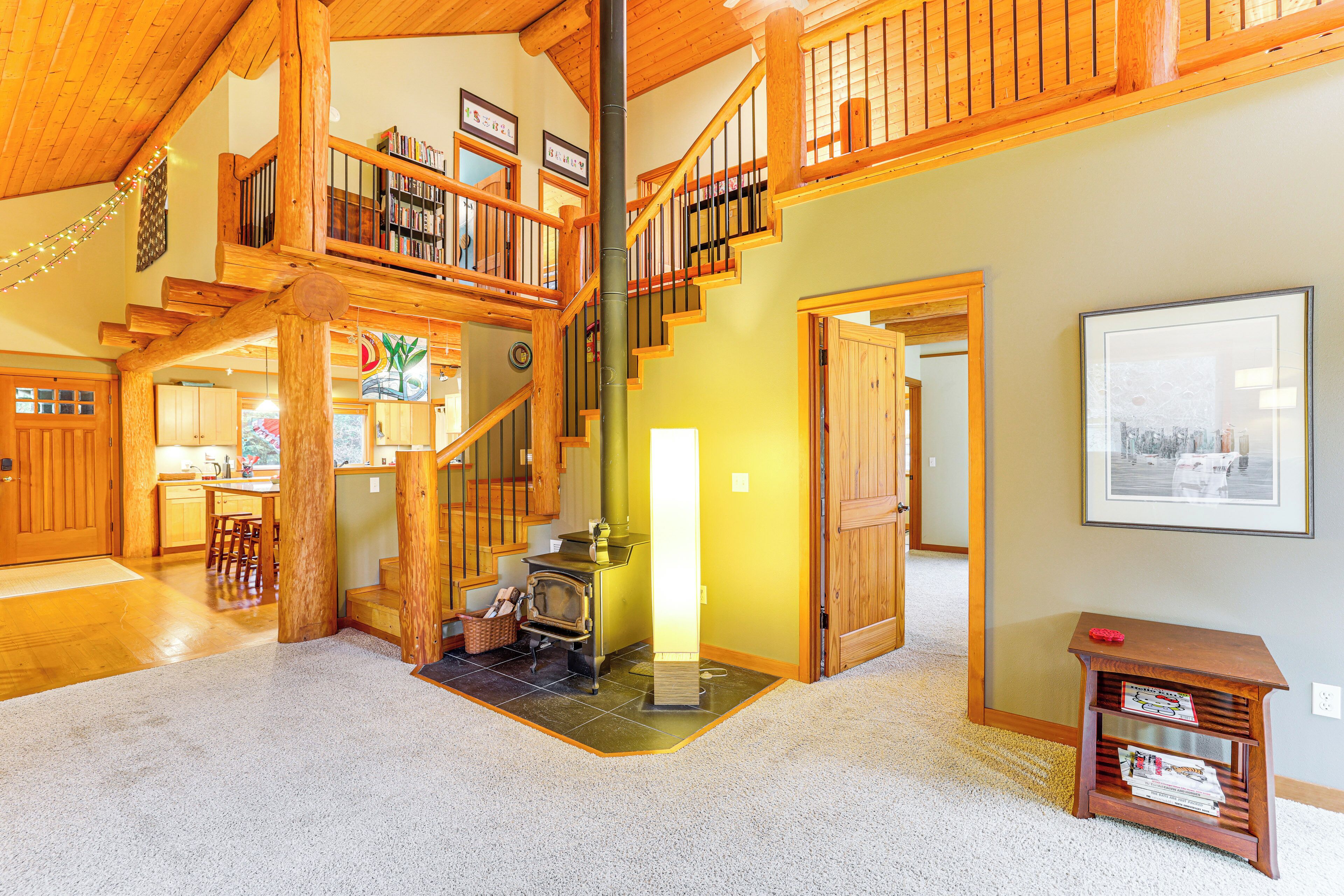 A spacious living area with a wooden staircase, a fireplace, and a bookshelf.