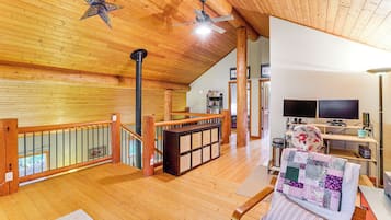 A spacious living area with a wooden ceiling, a fireplace, a television, and a comfortable seating area.