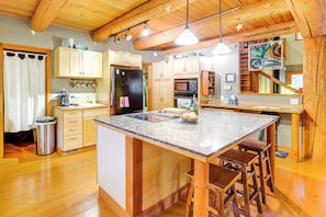 A kitchen with wooden cabinets, a central island with stools, a refrigerator, and a microwave. - 11 Mi to Olympic NP: Port Angeles Retreat w/ Deck (Port Angeles)
