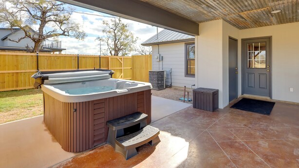 A hot tub with steps, a covered patio, and a door with a window. - Private Hot Tub & Pickleball Court: Baird Home! (Baird)