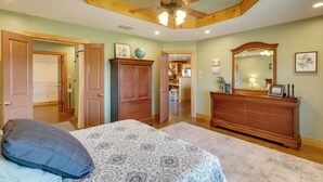 A bedroom with a bed, a dresser, a ceiling fan, and a large mirror. - Private Hot Tub & Pickleball Court: Baird Home! (Baird)