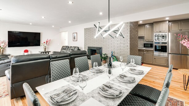 Una sala de estar moderna con comedor, chimenea y cocina equipada con electrodomésticos de acero inoxidable.