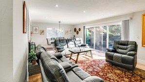 Una sala de estar moderna con un sofá modular, un sillón de cuero y una mesa de centro. Se ve una ventana grande con vistas al exterior.