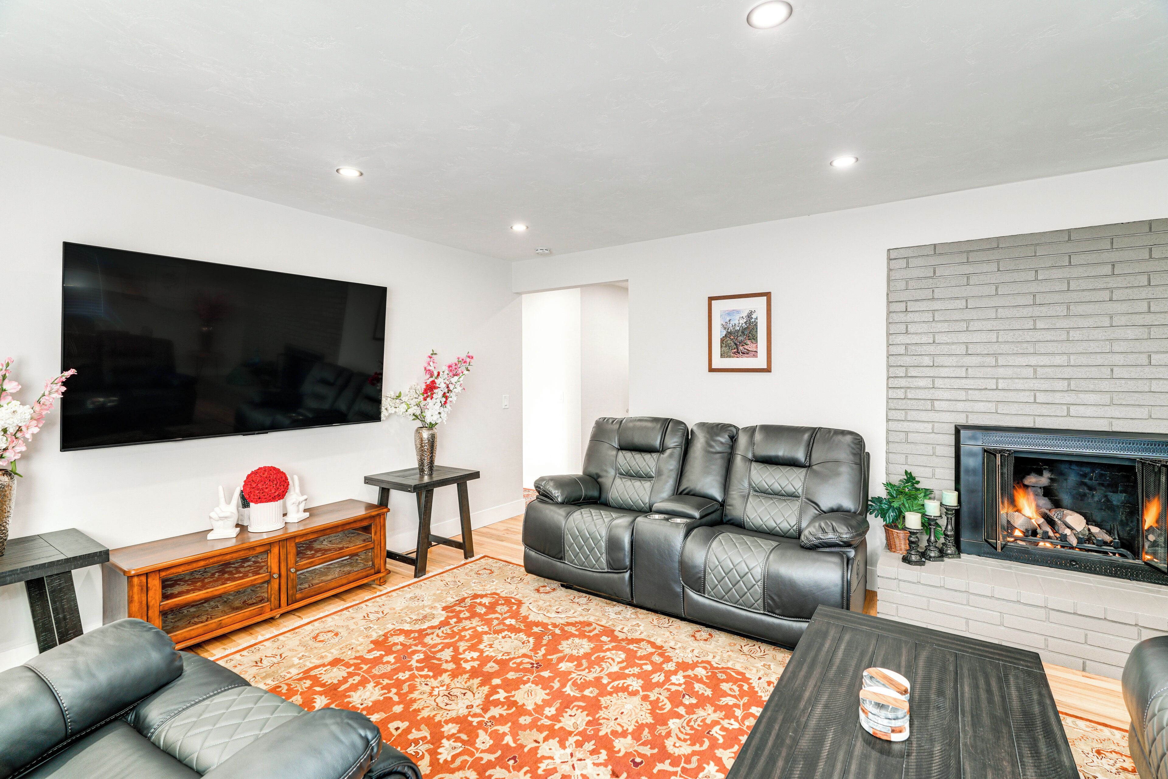 A living room with a flat-screen TV, leather sofa, fireplace, and a coffee table.