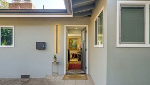 Una entrada de casa moderna con vista despejada al interior, una mesita lateral con una planta y un felpudo.