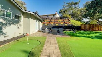 Enjoy a peaceful retreat with a patio area featuring outdoor seating and a golf bag, overlooking a beautifully landscaped garden.
