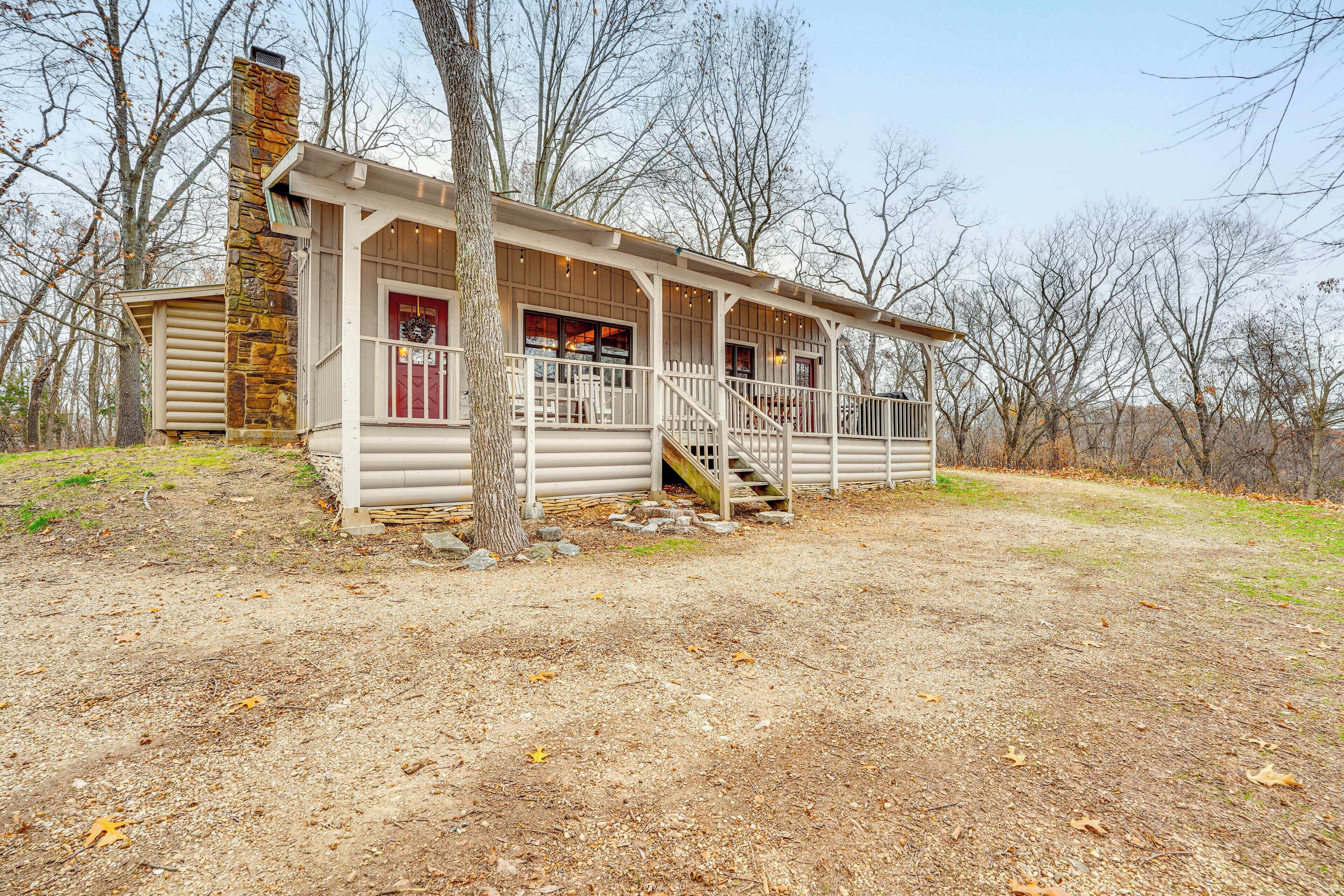 A log cabin with a porch, a stone chimney, and a staircase leading to the entrance.