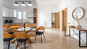 Une cuisine moderne avec des meubles blancs, une table à manger en verre et des chaises en bois.