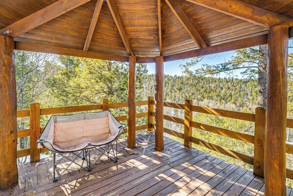 A wooden deck with a bench and a view of a forest.