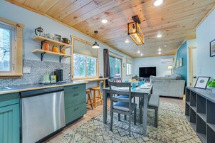 Una cocina moderna con armarios de madera, lavavajillas y un comedor con mesa y sillas.