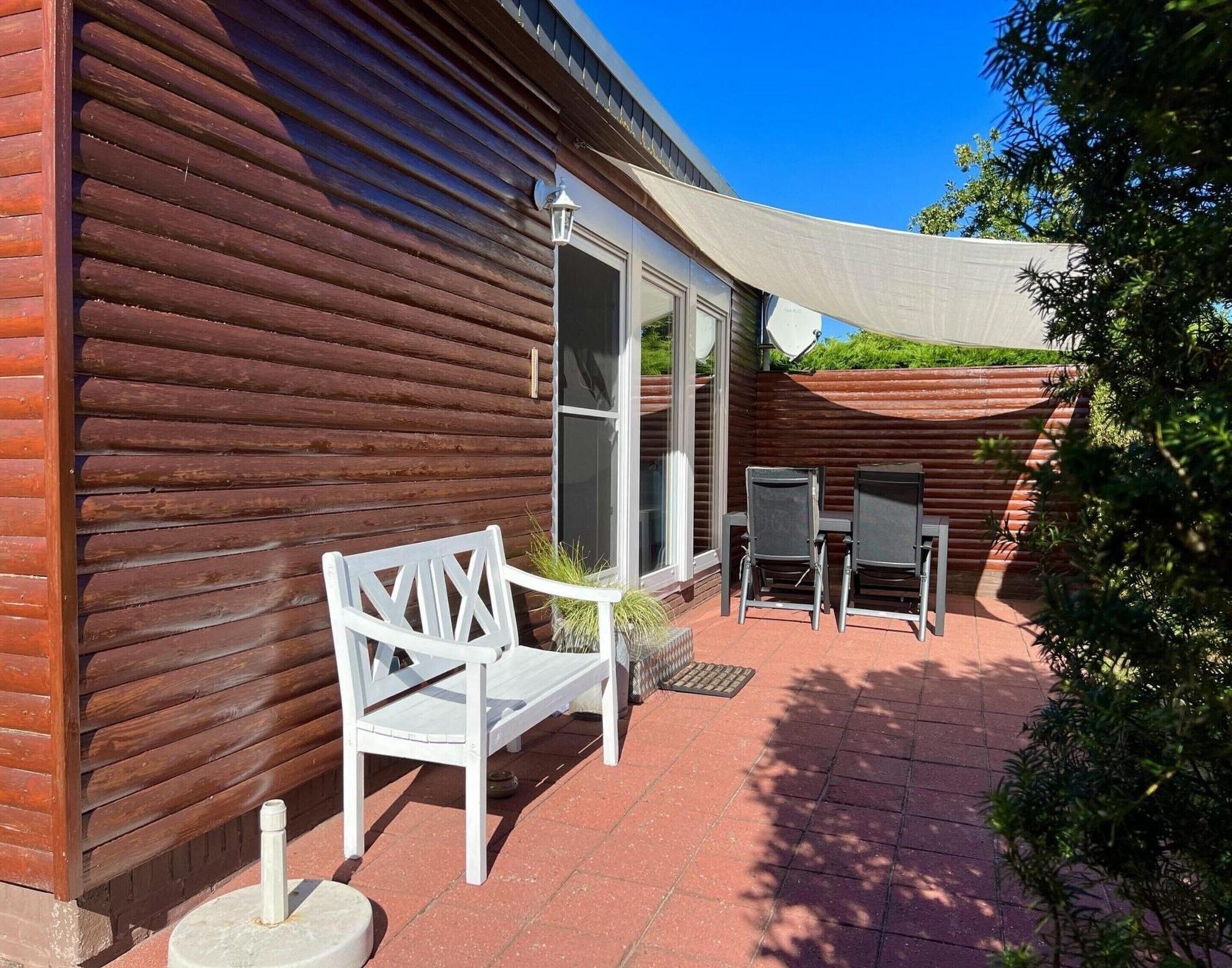 Una cabaña de madera con un patio que tiene dos sillas y una mesa.