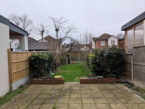 Enjoy a serene outdoor space with a paved patio, raised flower beds, and a yard surrounded by homes with unique architectural styles.