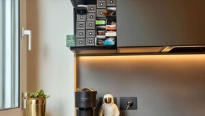 Una cocina con cafetera, una planta pequeña y una figura decorativa de un astronauta.