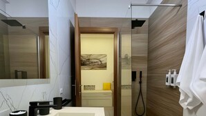 Une salle de bain moderne avec un lavabo blanc, des accessoires noirs, une douche en verre et un panneau mural en bois.